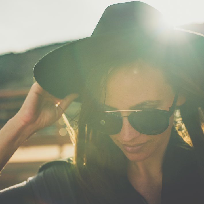 Woman with hat and sunglasses and her back to the light